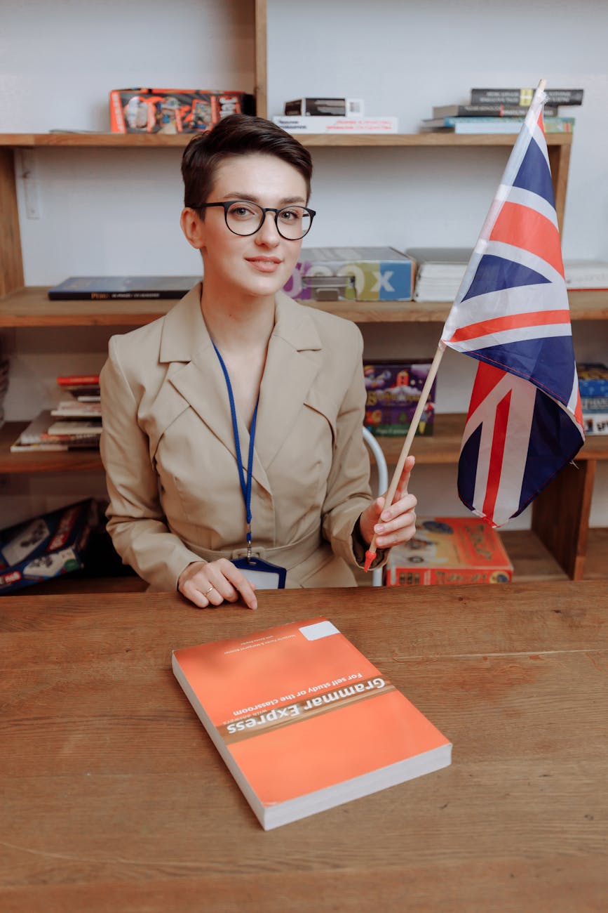 short haired woman wearing black framed eyeglasses holding a flag of united kingdom